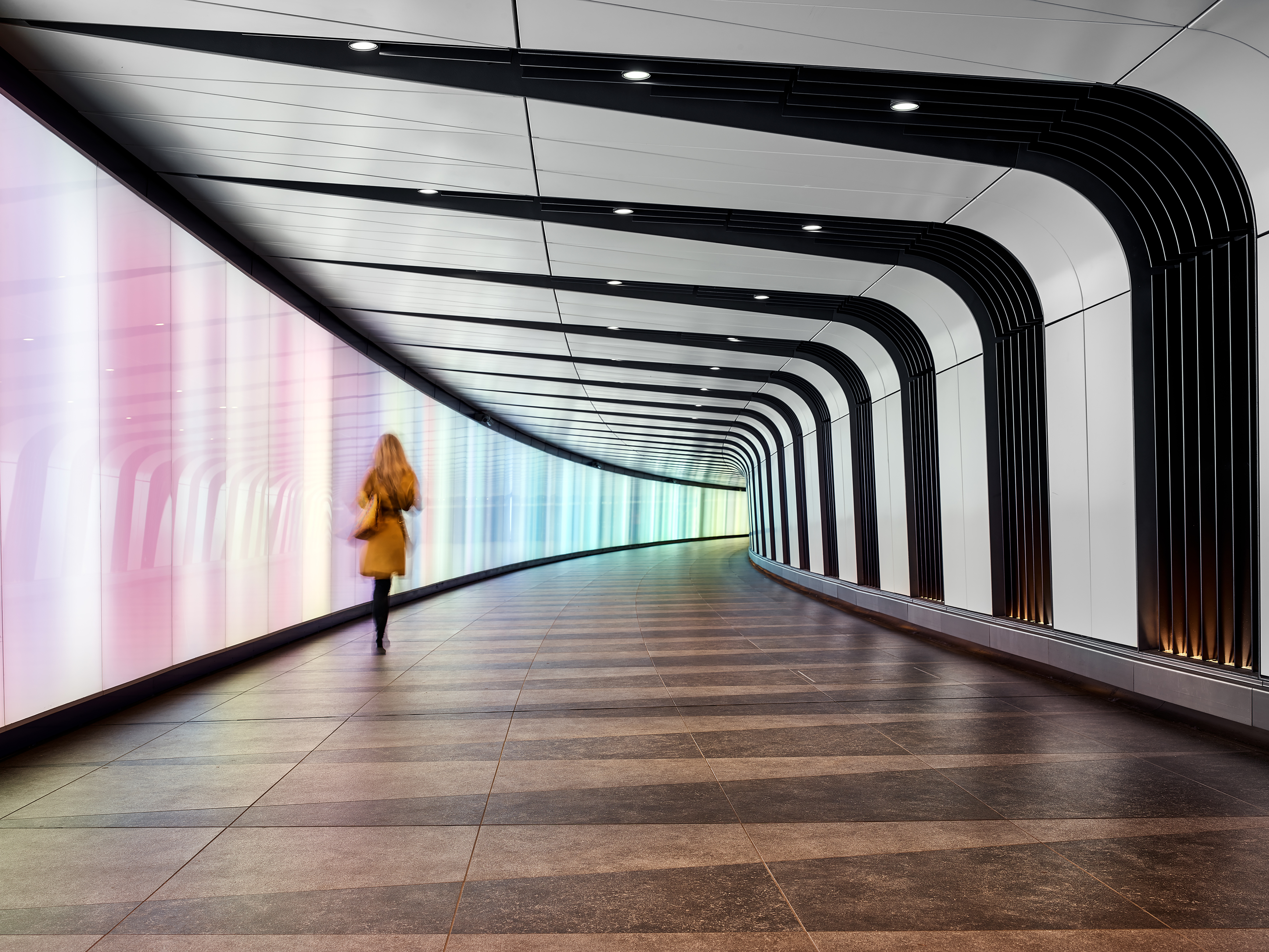 A person walking forward through a sleek, illuminated corridor — a calm, confident transition into a new chapter.